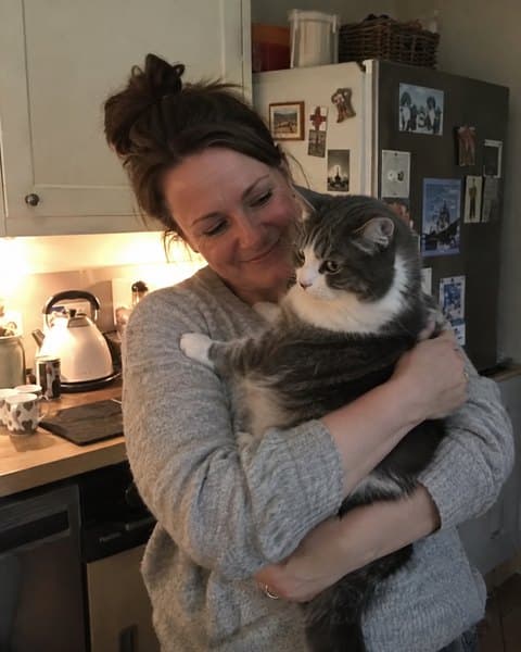 Helen holding her tabby cat in her kitchen.